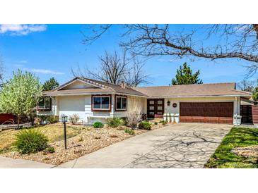 Charming single-story home featuring a well-manicured front yard, brown roof, and a two-car garage at 6963 E Heritage S Pl, Centennial, CO 80111