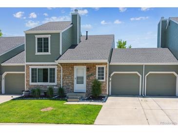 Charming home featuring stone accents, green siding, an attached two-car garage, and a well-manicured lawn at 4750 S Dudley St # 21, Littleton, CO 80123