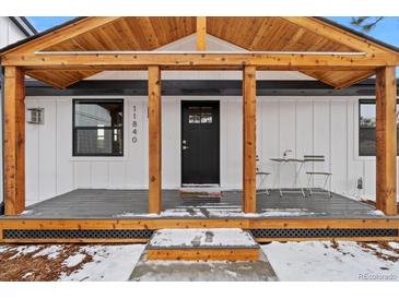 Inviting front porch with natural wood beams, a black front door, and table and chairs for outdoor seating at 11840 Elkhorn Dr, Franktown, CO 80116