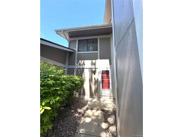 Inviting home entrance with gray walls, red door, and lush green shrubbery along the stone pathway at 2986 W 119Th Ave, Westminster, CO 80234
