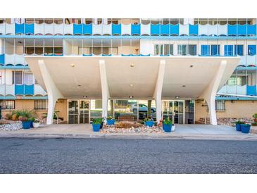 Modern high-rise building entrance with a covered walkway and well-maintained landscaping with planters at 1155 N Ash St # 908, Denver, CO 80220