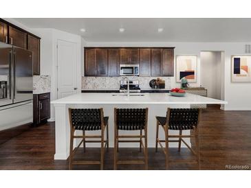 Bright eat-in kitchen with stainless steel appliances, island with chairs, and modern fixtures at 39743 Penn Rd, Elizabeth, CO 80107