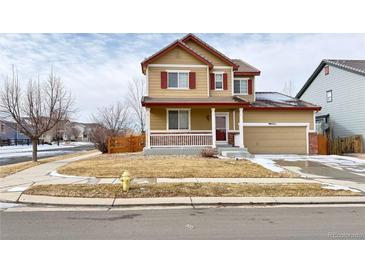 Two-story house with tan siding, red shutters, and a landscaped yard at 9821 Mobile St, Commerce City, CO 80022