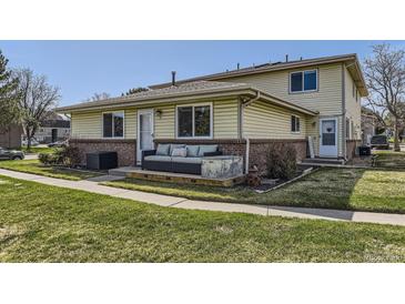 Charming exterior view of home with yellow siding, brick accents, and a cozy front porch with stylish outdoor seating at 3225 S Garrison St # 9, Lakewood, CO 80227