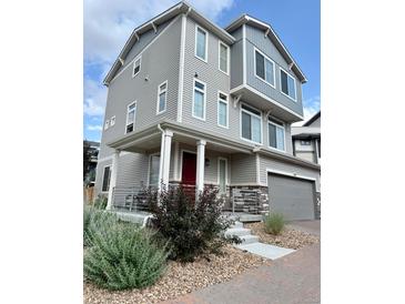 Charming three-story home featuring a covered front porch and attached two-car garage at 16362 E 111Th Dr, Commerce City, CO 80022
