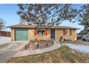 Charming brick home featuring a green garage door and contrasting wooden window shutters at 6431 W 77Th Pl, Arvada, CO 80003