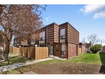 Charming brick townhome featuring well-maintained landscaping, fenced front yard and inviting entrance at 9338 W Utah Pl, Lakewood, CO 80232