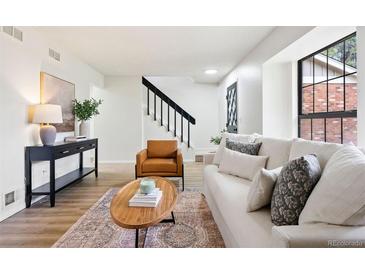 Bright living room featuring a comfortable white sofa, stylish furniture, and natural light from the window at 10310 E Jewell Ave # 57, Aurora, CO 80247