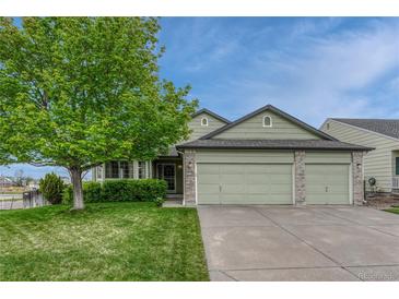 Charming green home featuring a lush front yard and a convenient three-car garage at 5350 S Quail Way, Littleton, CO 80127