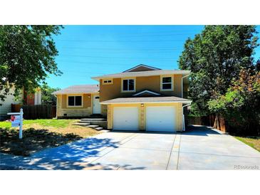 Two-story home with a two-car garage, yellow paint, stone accents and well-kept lawn and landscaping at 16800 E Bails Pl, Aurora, CO 80017
