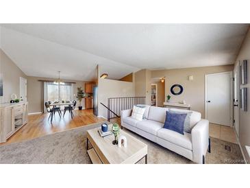 Inviting living room and dining area featuring sleek furniture, light colored walls, and lots of light at 11813 Bellaire Cir, Thornton, CO 80233