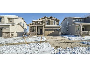 Two-story house with gray siding, stone accents, and a two-car garage at 238 Kino Court, Brighton, CO 80601