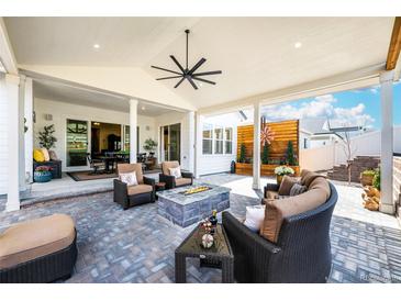 Inviting covered patio with a fire pit, comfortable seating, and stylish ceiling fan at 5707 Cadara Way, Parker, CO 80134