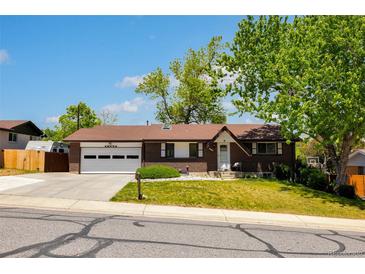 Charming brick home with attached two-car garage and well-manicured front lawn under a clear blue sky at 12771 W 6Th Pl, Lakewood, CO 80401