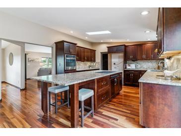 Open kitchen boasts dark wood cabinetry, granite countertops, stainless steel appliances, and a spacious island at 40192 Margaret Dr, Elizabeth, CO 80107