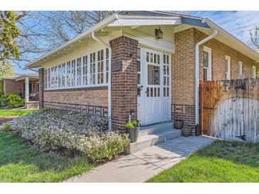 Charming brick home features a white-framed glass door and sunroom with a well-manicured lawn at 1230 S Emerson St Dr, Denver, CO 80210