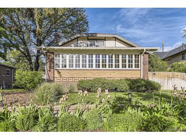 Charming brick home featuring a wall of windows and landscaped front yard with colorful flowers, creating inviting curb appeal at 1230 S Emerson St Dr, Denver, CO 80210