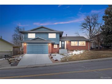 Two-story home features brick accents, an attached garage, and a well-maintained front yard at 1513 S Beech St, Lakewood, CO 80228