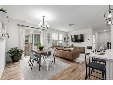 Bright, modern living space with hardwood floors, dining area, and a comfortable brown leather couch at 13860 Ash Cir, Thornton, CO 80602