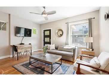 Bright living room features a grey sofa, ceiling fan, modern rug, and hardwood floors at 2645 W 24Th Ave, Denver, CO 80211