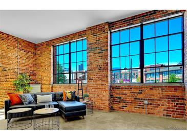 Bright living room featuring exposed brick walls, large windows, and stylish modern furnishings at 2500 Walnut St # 102, Denver, CO 80205