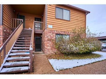 Cozy two-story condo with wood siding, brick accents, and snowy landscaping at 2277 S Buckley Rd # 102, Aurora, CO 80013