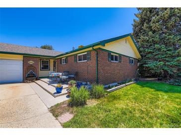 Charming brick home with green trim, lush lawn, and outdoor seating area at 10684 Downing St, Northglenn, CO 80233