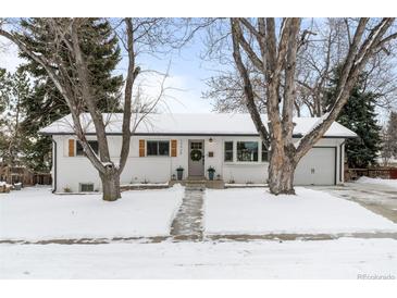 Charming single-story home featuring white paint, a gray door and shutters and a snow-covered front yard at 13438 W 23Rd Pl, Golden, CO 80401