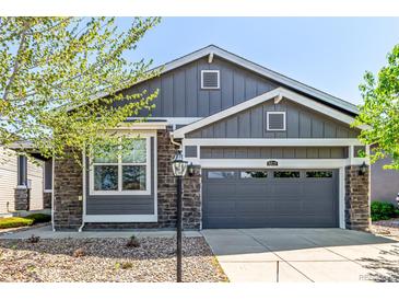 Charming exterior view of gray home with a two car garage, stone accents, and well-manicured landscaping at 15122 Uinta St, Thornton, CO 80602