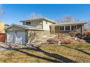 Charming multi-level home boasts a well-maintained lawn, brick accents, and an attached two-car garage at 10596 Ura Ln, Northglenn, CO 80234