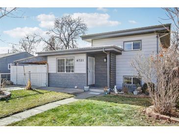 Ranch style home with gray exterior and landscaped lawn at 6721 Birch St, Commerce City, CO 80022