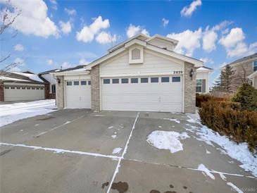 Brick house with 3-car garage, snowy front yard, and landscaping at 2020 Alpine Dr, Erie, CO 80516