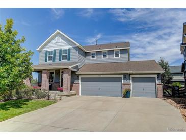 Charming two-story home featuring a three-car garage, inviting front porch, and manicured lawn on a sunny day at 4858 S Tibet St, Aurora, CO 80015