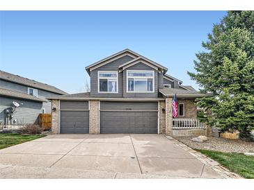 Two-story home featuring a three car garage, neutral paint, well maintained landscaping, and an American flag at 6530 S Tabor St, Littleton, CO 80127