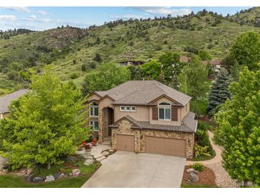 Inviting two-story home with a stone-accented facade, mature trees, and a two-car garage at 19061 Eagle Ridge Dr, Golden, CO 80401