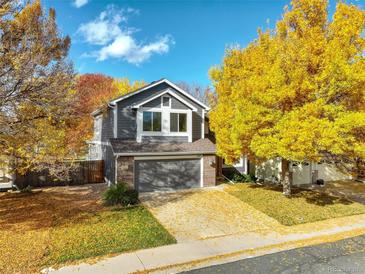Charming two-story home featuring fall foliage, manicured lawn, and attached two-car garage on a sunny day at 10971 Bryant St, Westminster, CO 80234