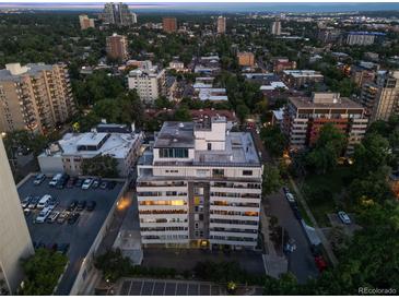 Aerial view of a condominium building with parking and the city in the background at 740 N Pearl St # 606, Denver, CO 80203