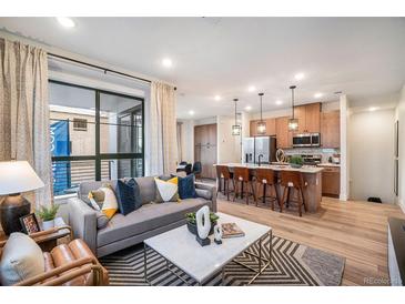 Open-concept living room flows into the kitchen with a large window and contemporary furnishings at 2036 S Holly St # 1, Denver, CO 80222
