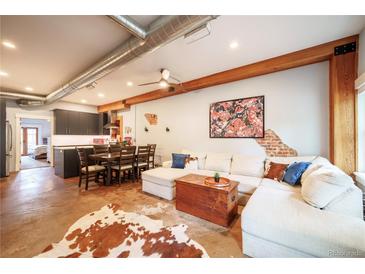 Open concept living room featuring modern decor, wood beams, concrete floors, and a stylish area rug at 117 Elati St # 1, Denver, CO 80223