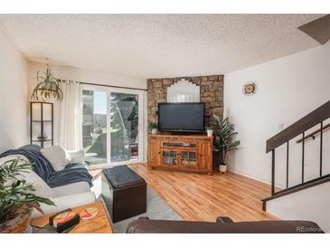 Bright living room featuring hardwood floors, a stone accent wall, and sliding glass doors to the outside at 3506 S Depew St # 3, Denver, CO 80235