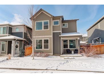 Two-story home with gray siding, snowy front yard, and small patio at 6727 Canosa St, Denver, CO 80221