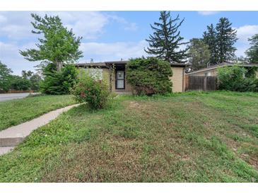Charming brick home featuring a well-maintained front yard with mature trees and a walkway at 588 Empire St, Aurora, CO 80010