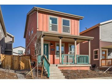 Charming two-story home features a welcoming front porch with teal railing and a vibrant coral exterior at 10331 E 62Nd Pl, Denver, CO 80238