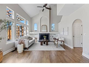 Bright living room with vaulted ceilings, large windows, and fireplace with built-in shelving at 7071 S Gibraltar Way, Centennial, CO 80016