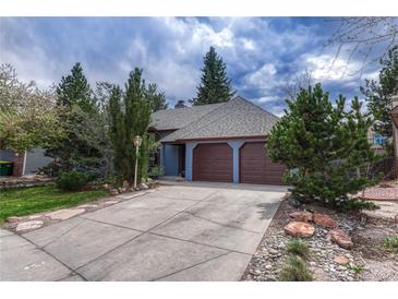 Charming single-Gathering home featuring a two-car garage, lush landscaping, and classic architectural details at 11838 W Arlington Dr, Littleton, CO 80127