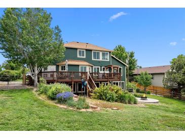 Expansive backyard featuring a wooden deck, fire pit, lush landscaping, and mature trees at 603 E 2Nd Ave, Castle Rock, CO 80108