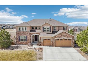 Inviting two-story home featuring a three car garage, stone accents, and manicured landscaping at 11938 S Meander Way, Parker, CO 80138