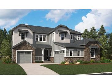 Charming two-story home with stone accents, gray siding, well-manicured lawn, and a spacious three-car garage at 9255 Ironwood St, Highlands Ranch, CO 80129