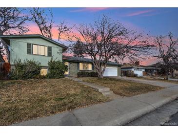 Ranch style home with green exterior, attached garage, and landscaping at 11921 W 70Th Pl, Arvada, CO 80004