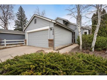 Charming home featuring a grey exterior, well-maintained landscaping, and an attached two-car garage at 10450 W 81St Pl, Arvada, CO 80005